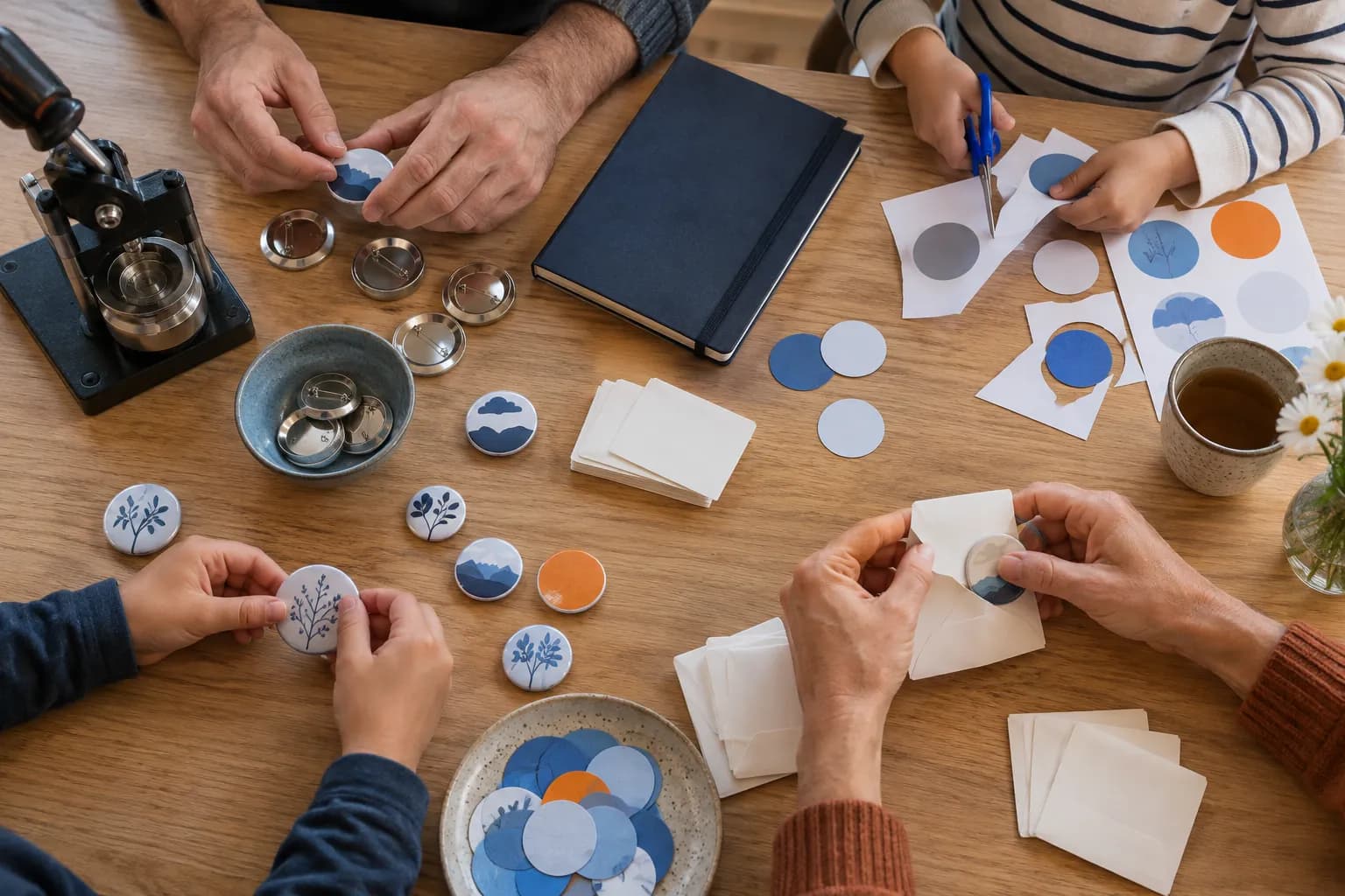 Hands around a kitchen table cutting paper circles and assembling pin-back buttons together